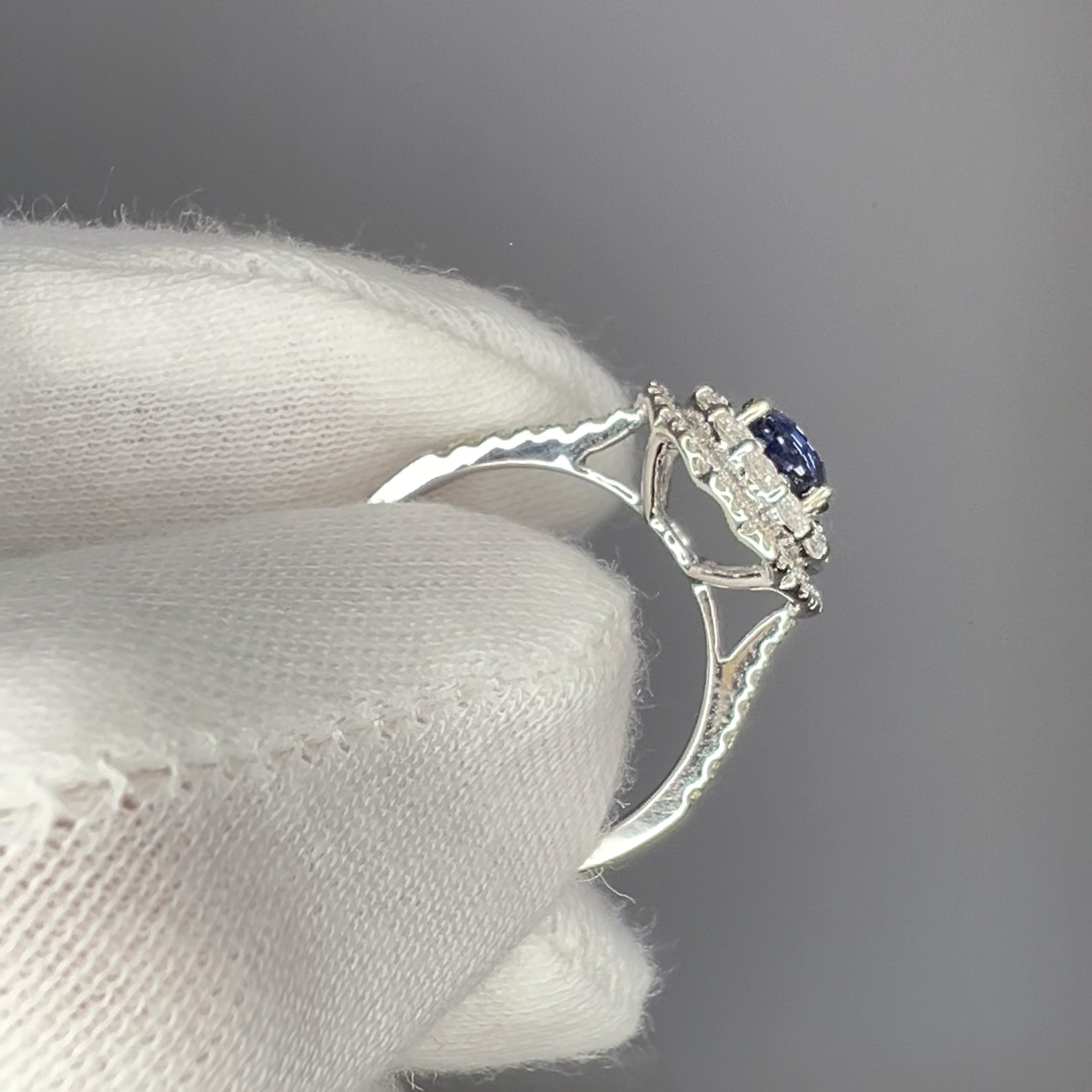 Cobalt blue spinel engagement ring held in white gloves