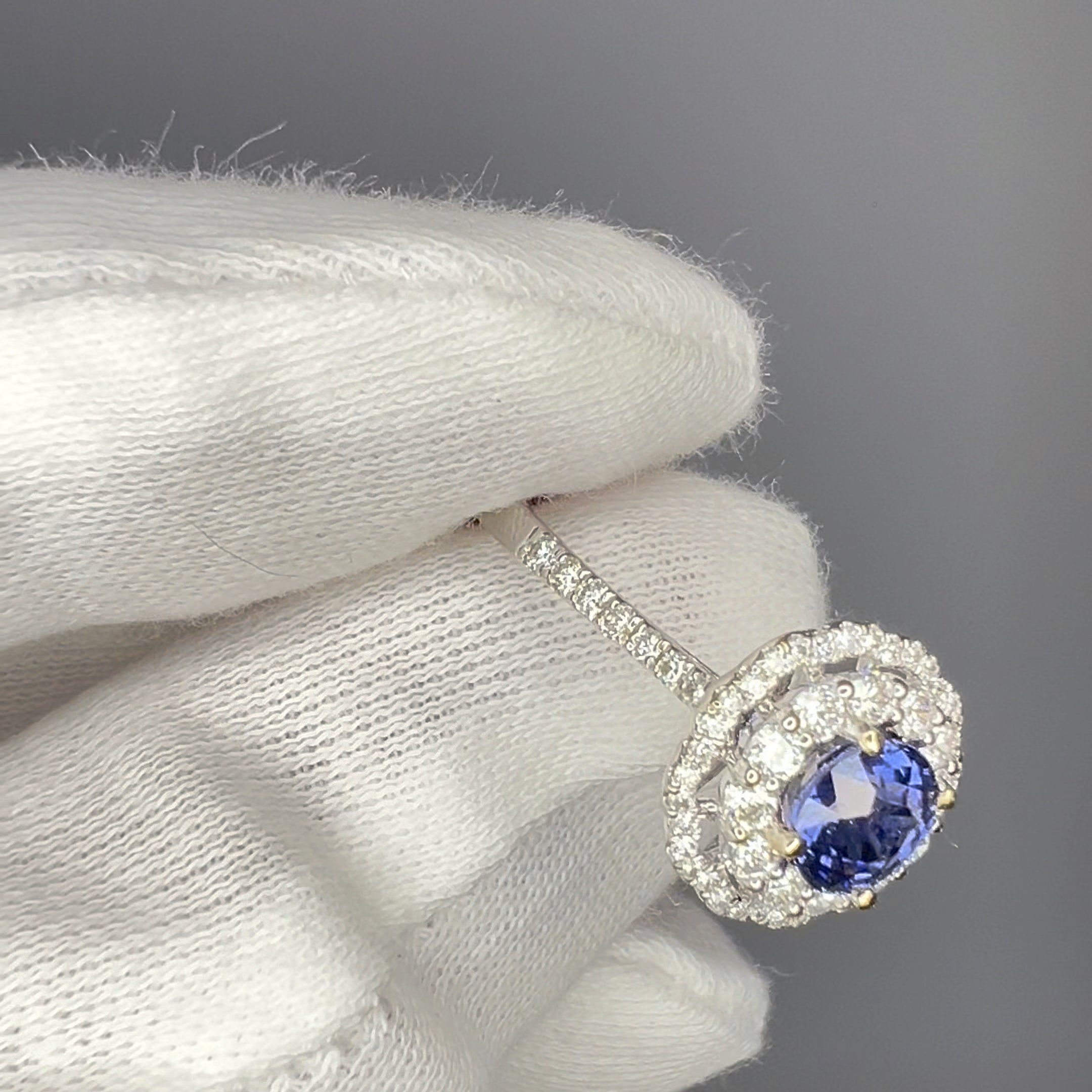 Cobalt blue spinel engagement ring held in white gloves