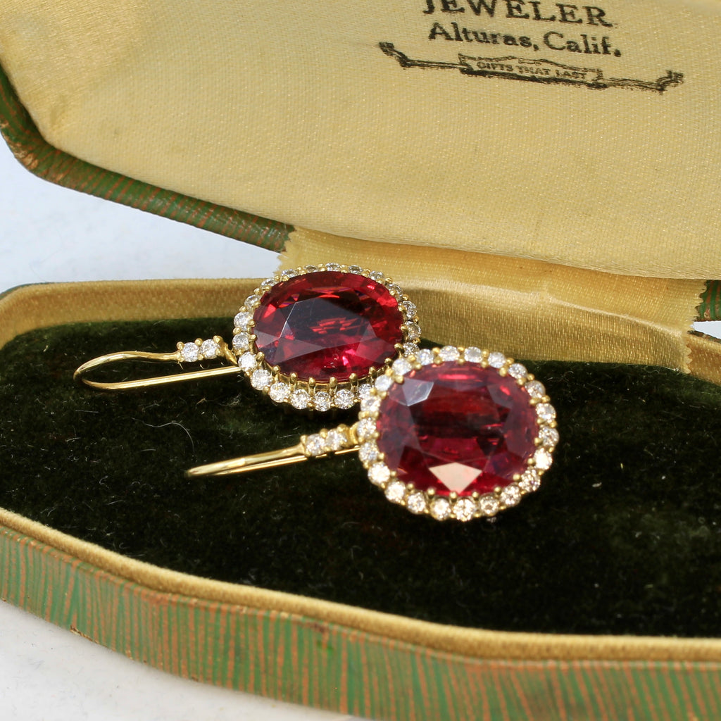 Rubellite dangle earrings in an antique jewelry box. Made of 14K yellow gold and accented with round diamonds.