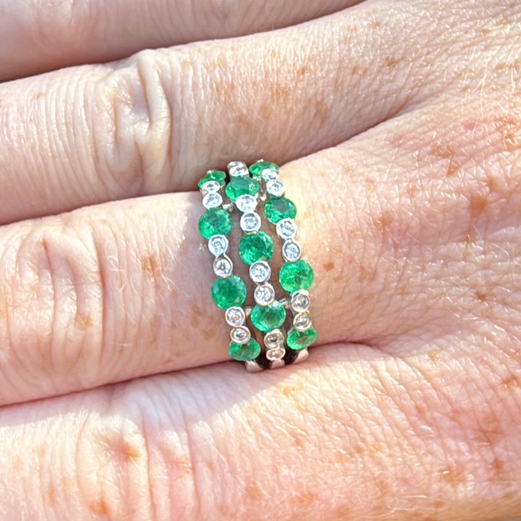 Green emerald diamond and white gold ring on hand top view