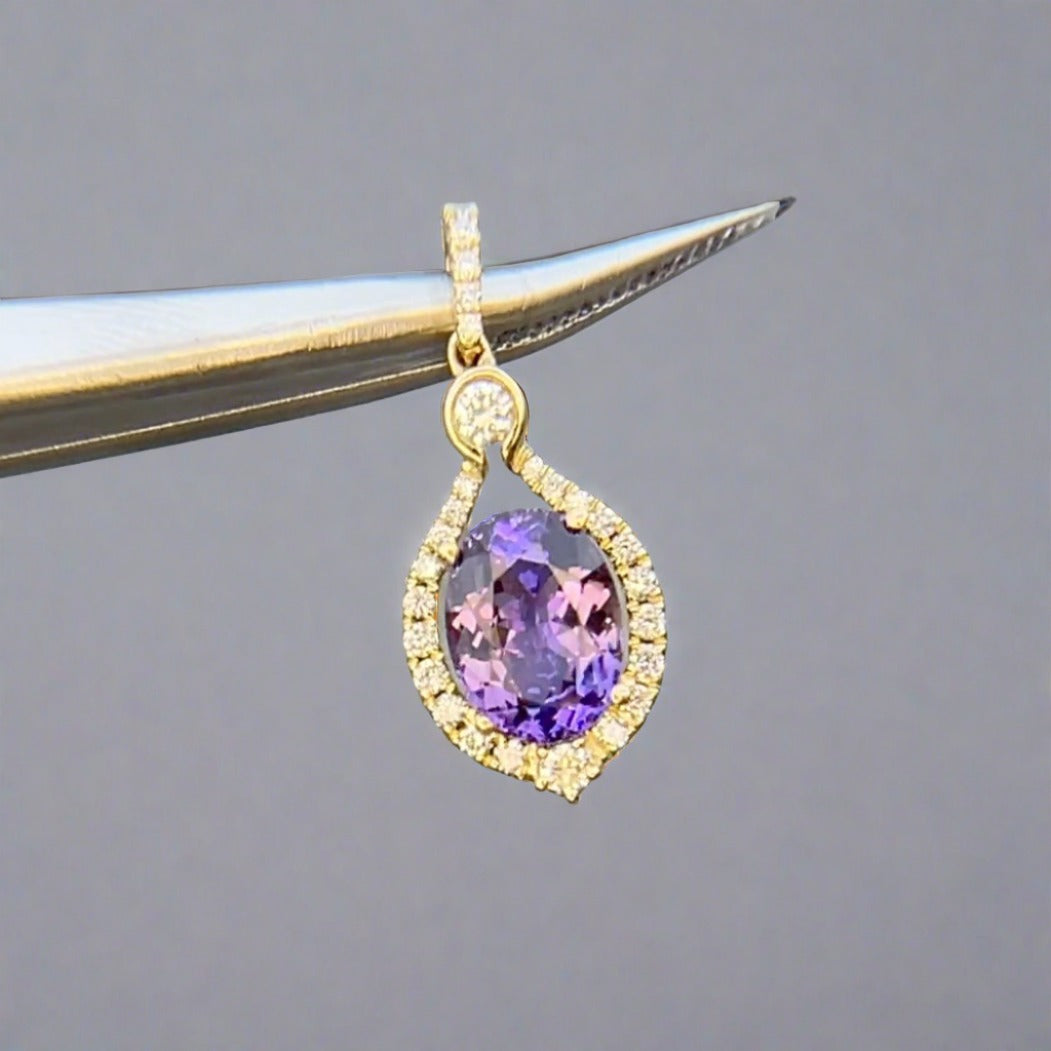 Fancy pinkish purple tanzanite pendant made with 14 yellow gold and accented with diamonds