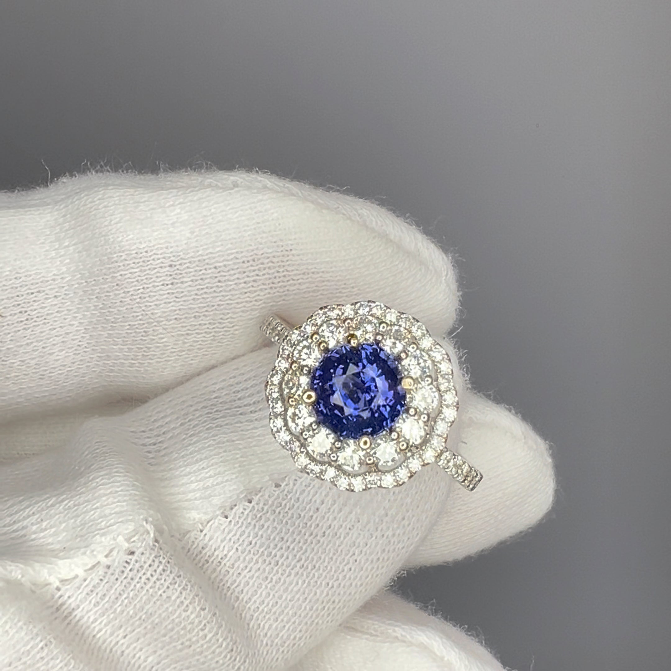 Cobalt blue spinel engagement ring held in white gloves