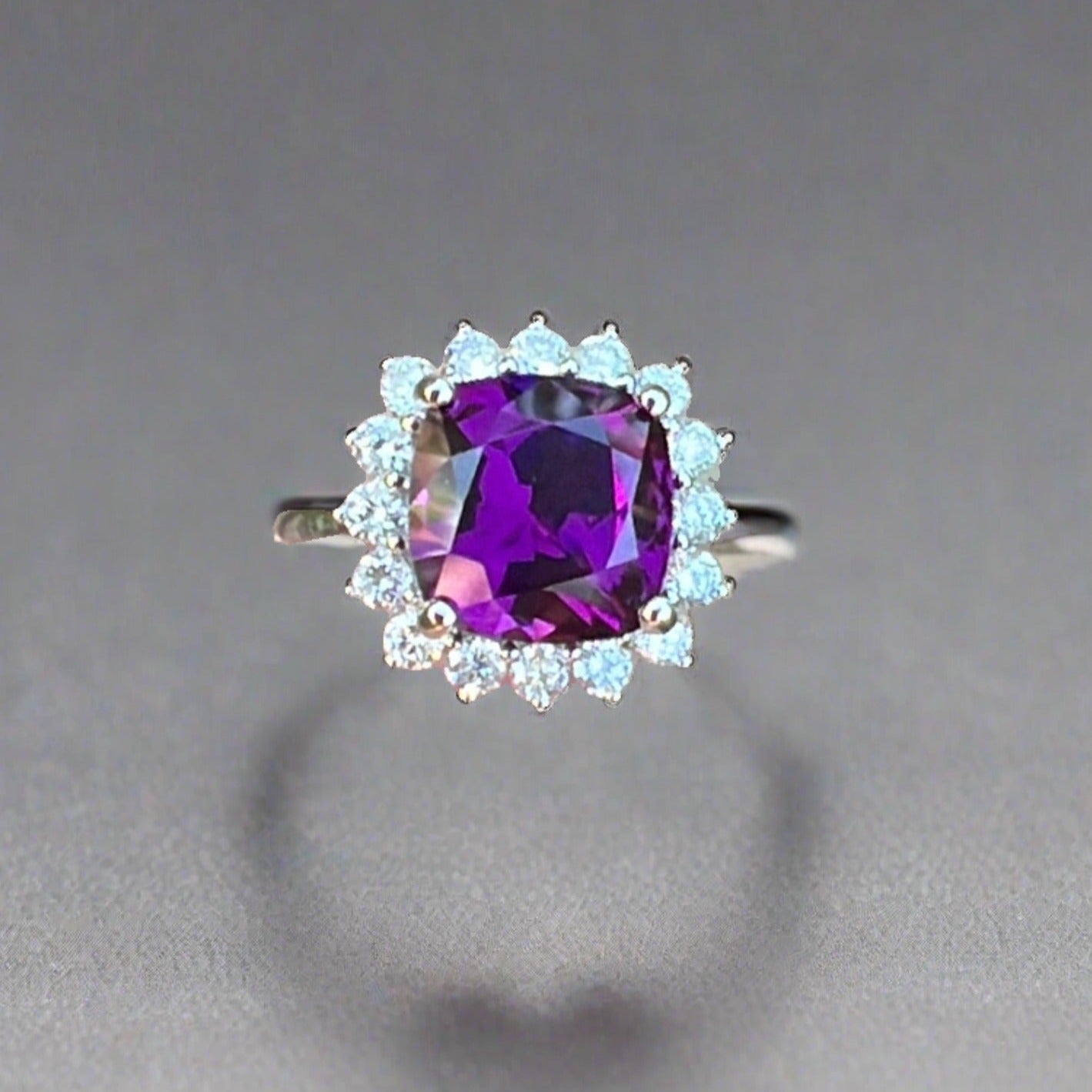 Royal purple grape garnet ring with a diamond halo set in 14k white gold with a grey background and a shadow