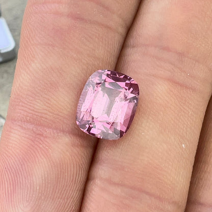 Loose Gemstone Pink Malaya Garnet in hand with outdoor lighting