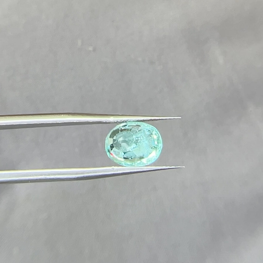 Paraiba Tourmaline Oval held by tweezers showing the backside of the gemstone
