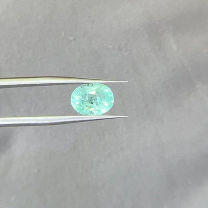 Paraiba Tourmaline Oval held by tweezers showing the nice blue color